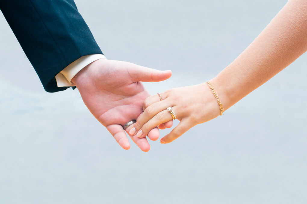 unique wedding ring shot with bride and groom hands together 