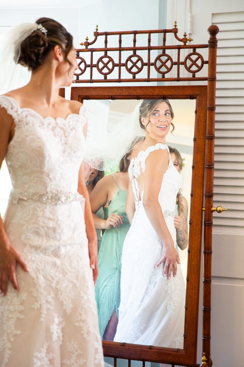 bride looks in mirror getting ready for Southern Pines wedding at the Weymouth Center
