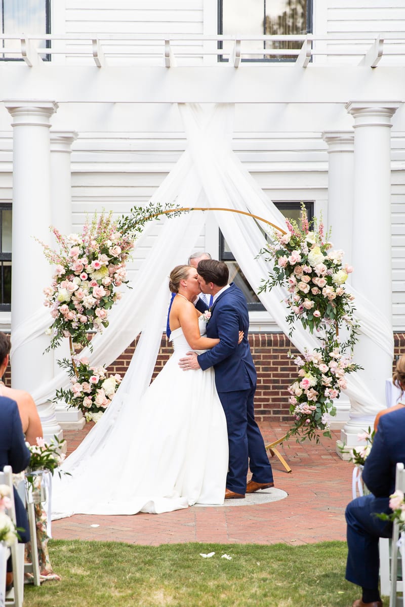 pink and white ceremony arch at Pinehurst wedding first kiss