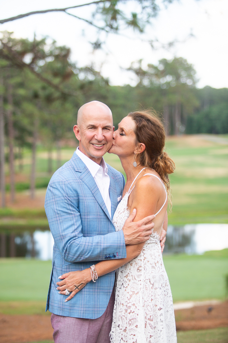 bride kissing groom on cheek at wedding in Forest Creek Golf Club in Pinehurst