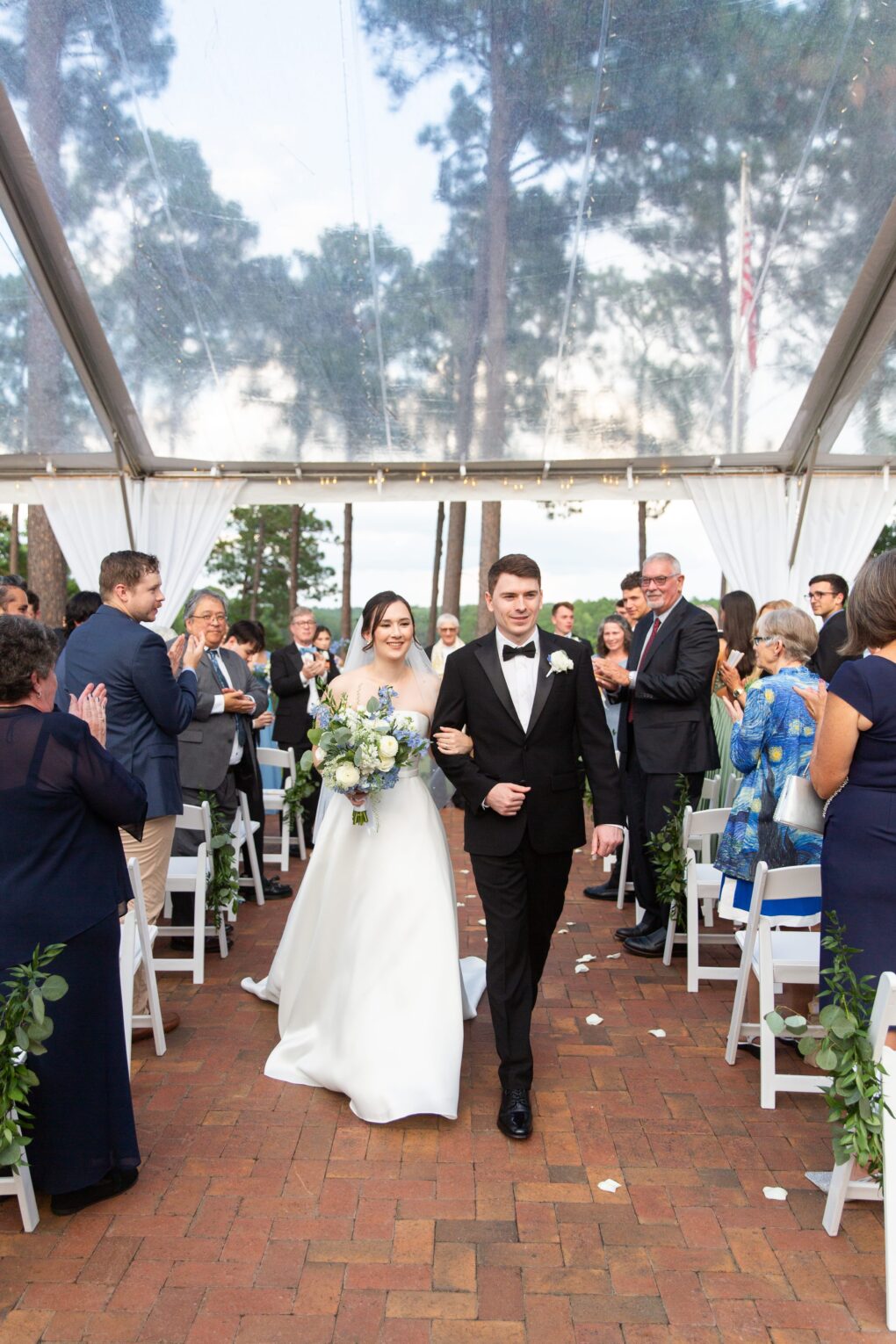 recessional at CCNC wedding ceremony on brick patio under clear tent