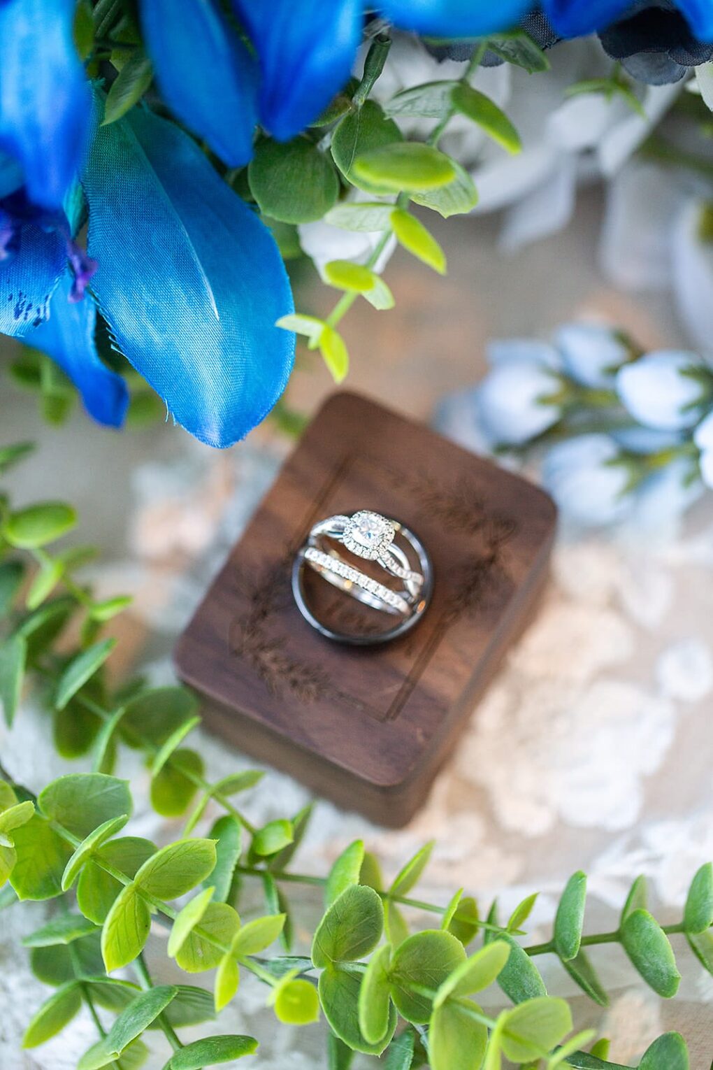 wedding rings on wooden wedding ring box with blue wedding flowers