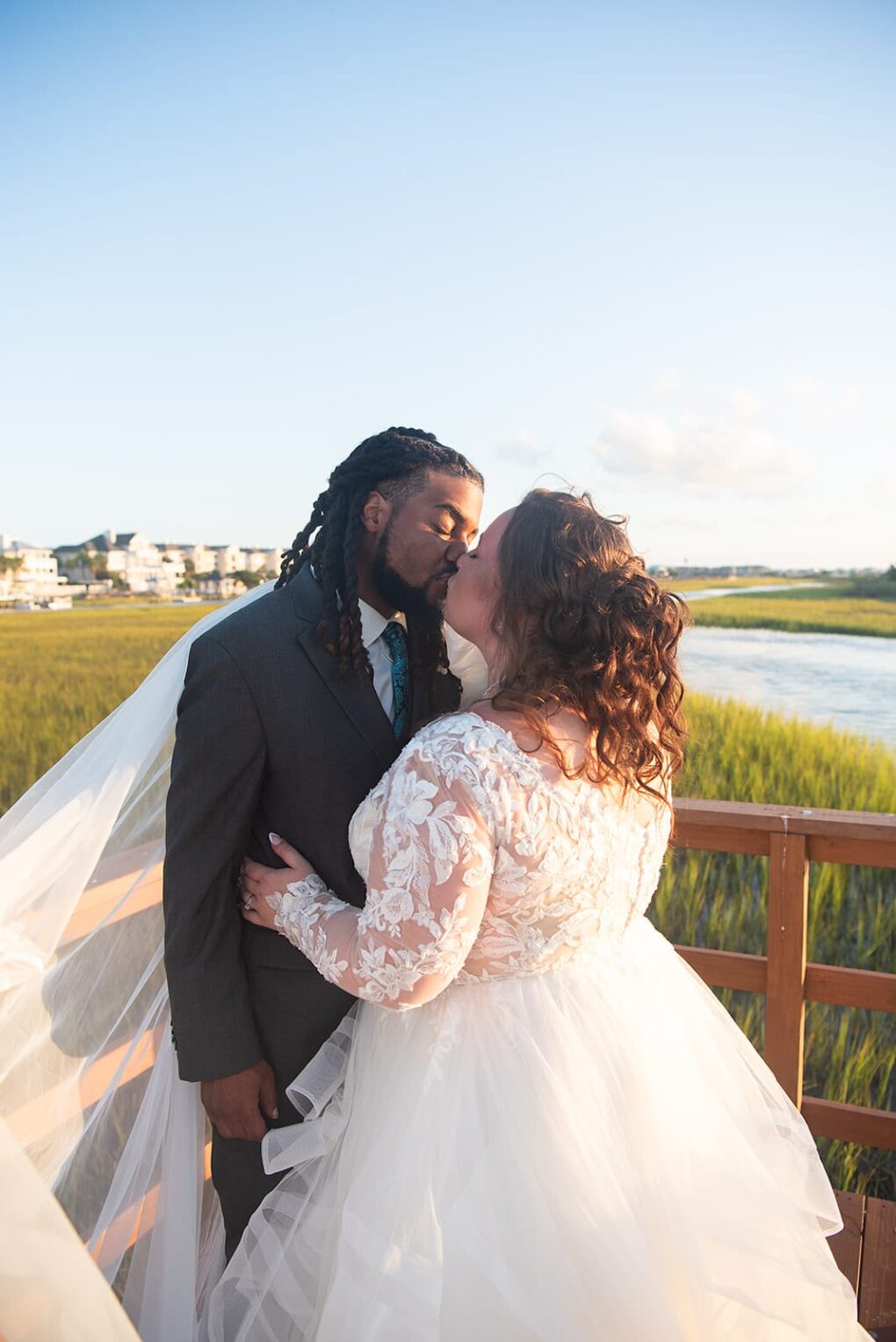 bride and groom kissing on pier Wrightsville beach, North Carolina