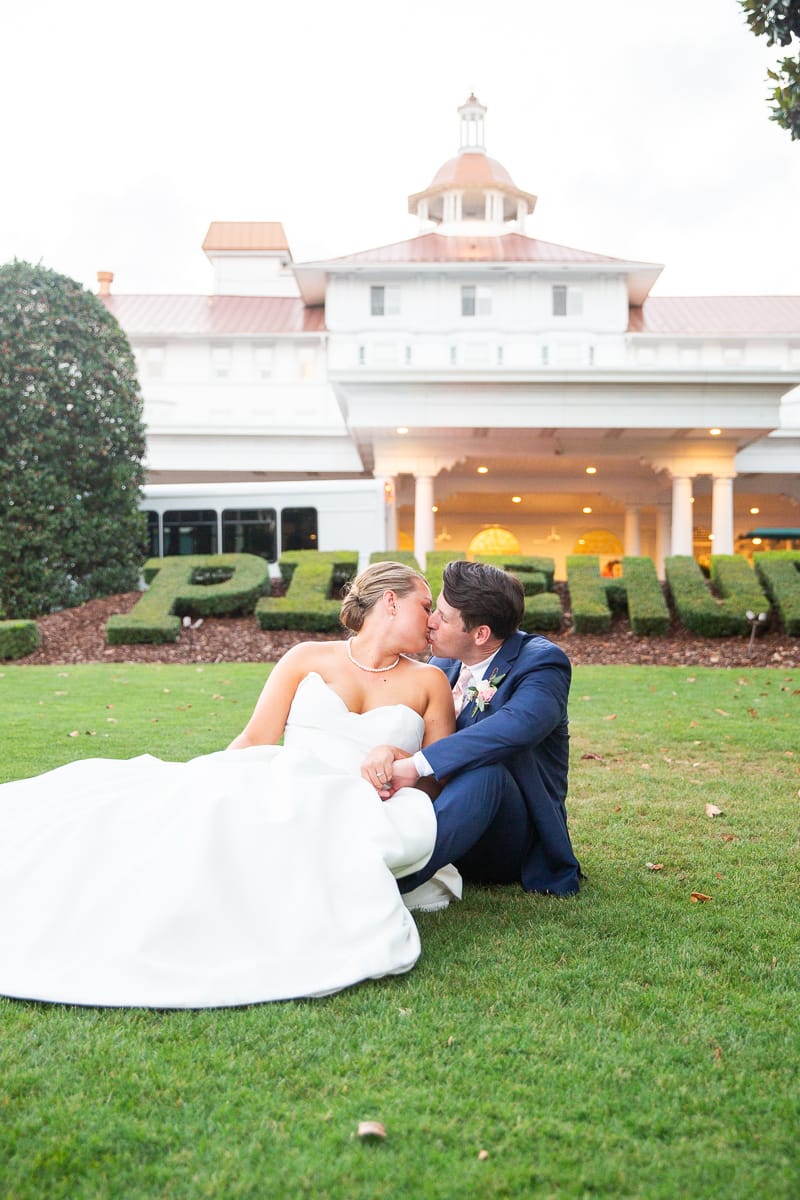 bride and groom kissing in front of the iconic Pinehurst hedge at the Carolina Inn during a Pinehurst wedding