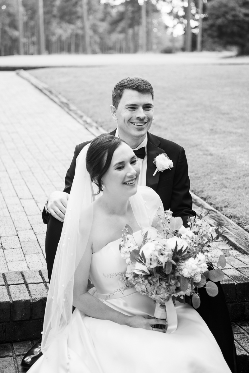 Black-and-white portrait of the wedding couple sitting together at the Country Club of North Carolina.