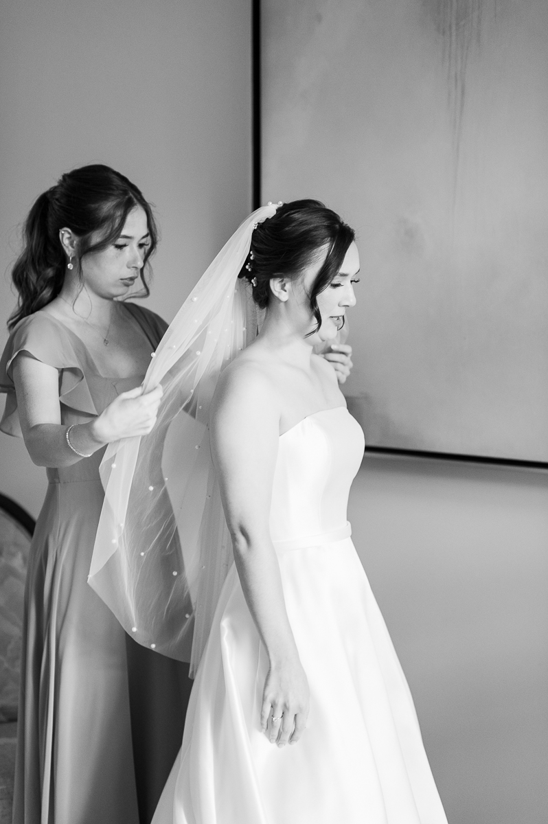 Black and white photo of the bride admiring her wedding gown during preparations at a Pinehurst wedding.