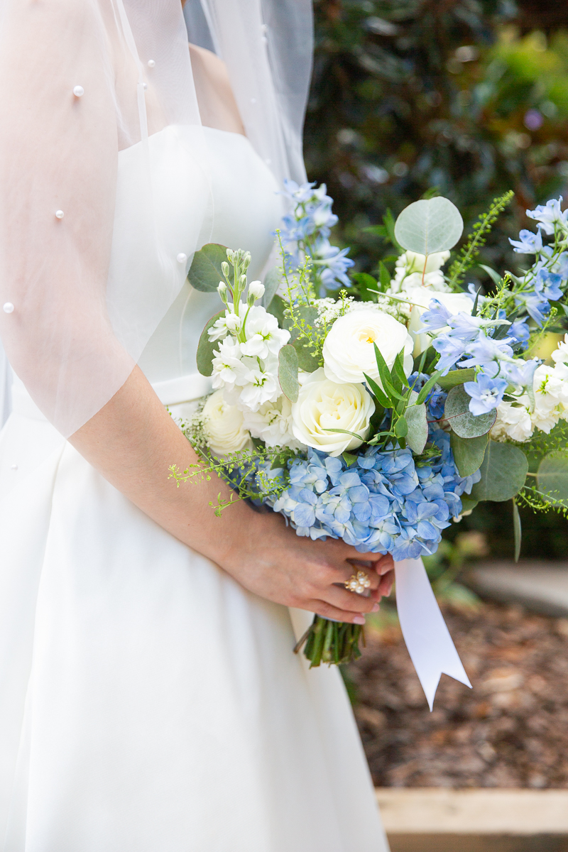 Bride holding a blue and white floral bouquet.