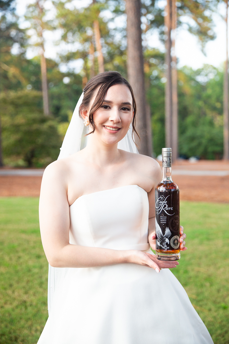 Bride holding a custom bourbon bottle during her Pinehurst wedding at the Country Club of North Carolina.