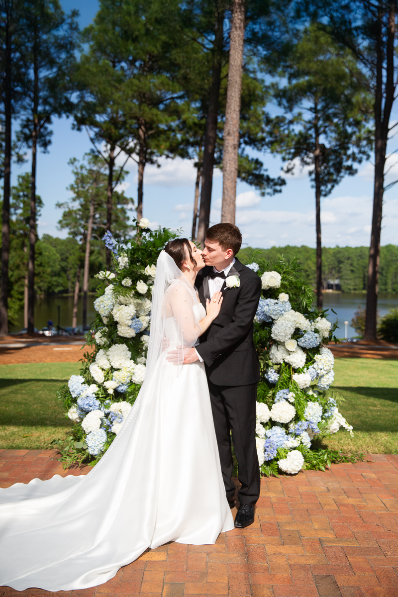 Wedding vows exchanged in front of a floral arch outdoors at the Country Club of North Carolina.