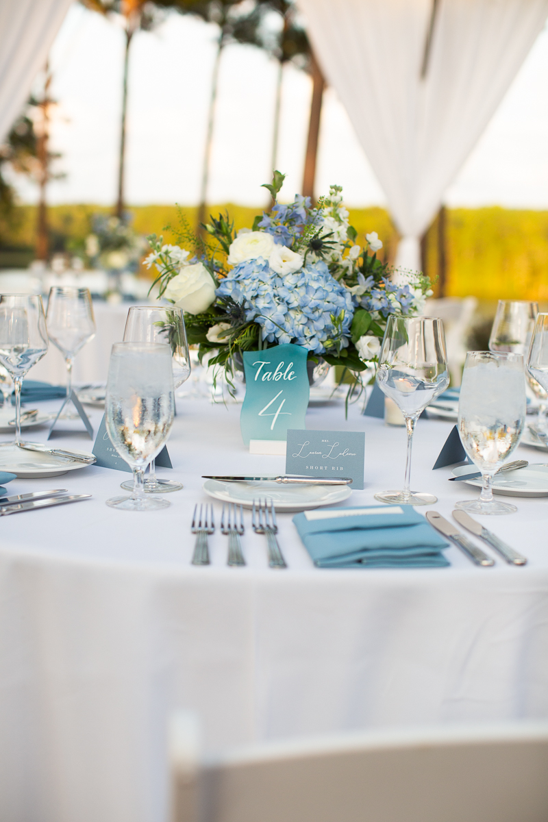 Floral centerpiece with a blue menu card on a wedding table.