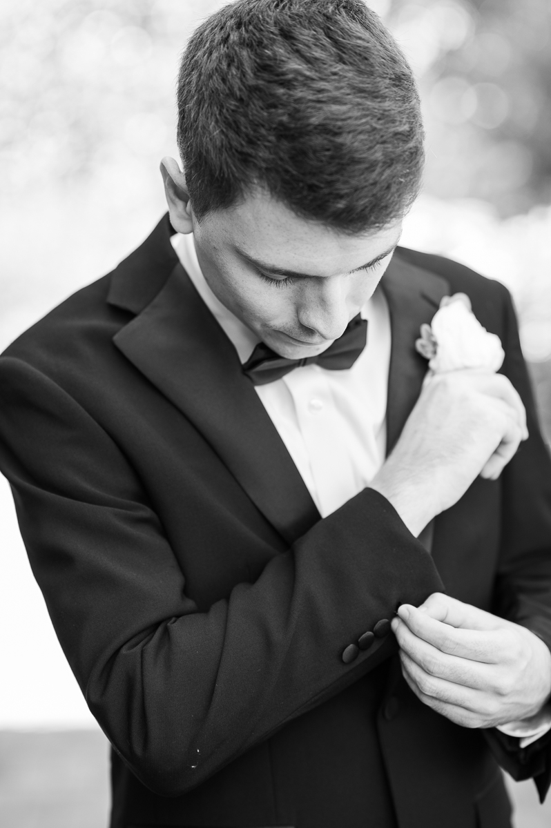 Black-and-white photo of the groom adjusting his cufflinks before the wedding at CCNC.