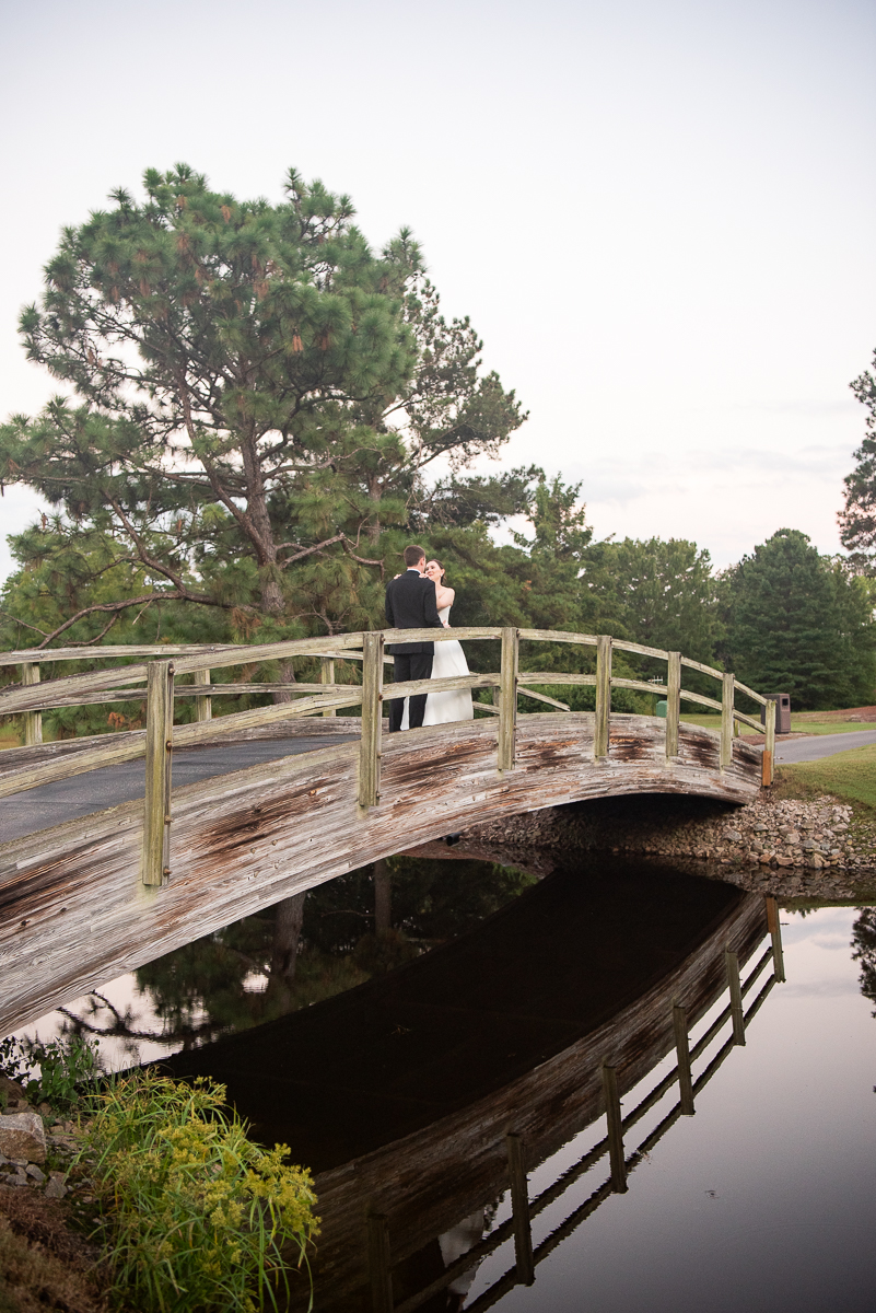 Romantic photo of a couple on a wooden bridge at the Country Club of North Carolina.