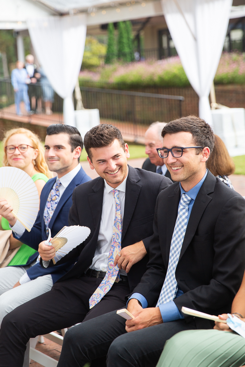 Wedding guests smiling and seated during a ceremony at the Country Club of North Carolina.