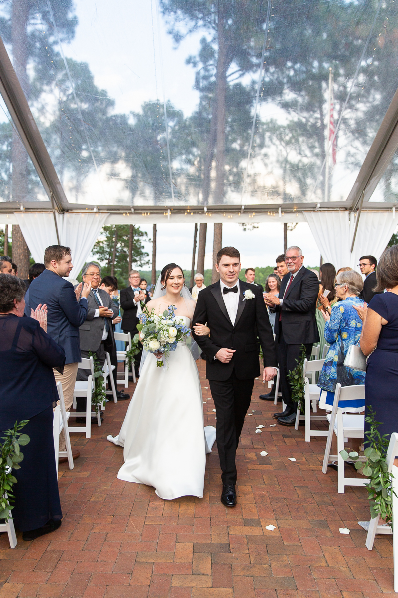 Wedding recessional with bride and groom walking down the aisle surrounded by guests